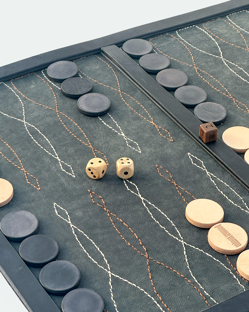 Black saddle stitch backgammon board set up for play, angled view